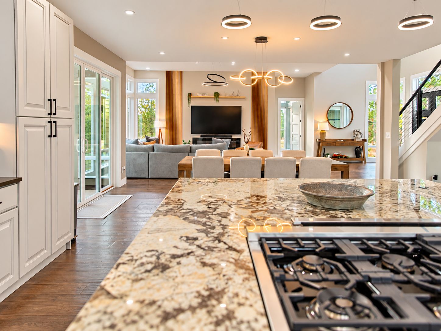 A modern kitchen with a large island, built-in appliances, and a dining area with a sofa and chairs.