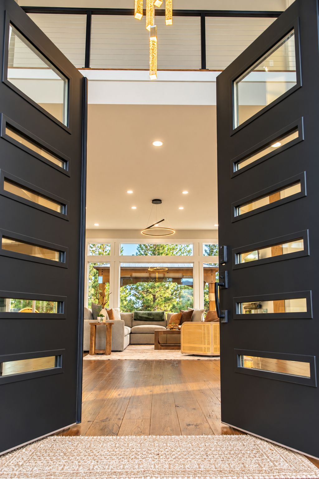 A modern interior with a large open doorway, recessed ceiling lights, and a view of an outdoor area with trees.