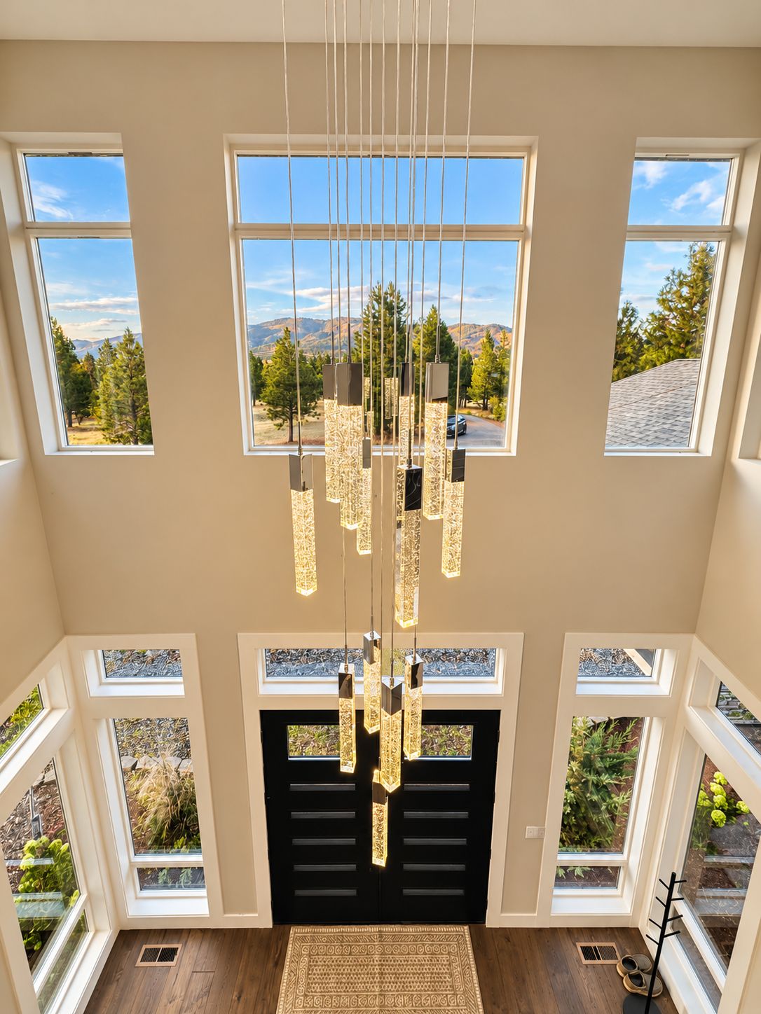 A spacious room with multiple windows offering a mountain view, a modern chandelier, and a fireplace.