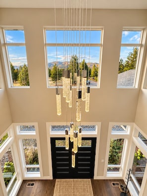 A spacious room with multiple windows offering a mountain view, a modern chandelier, and a fireplace.