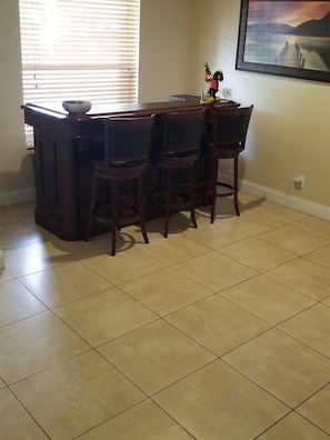 A kitchen with a bar area, four chairs, a sink, and a window with blinds. - 3-bedroom house in beautiful Hollywood Florida (Hollywood)