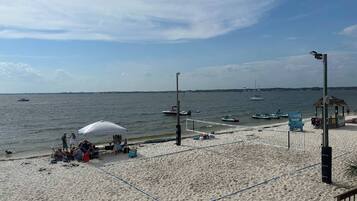 A beach with a volleyball net, a tent, and boats in the water.