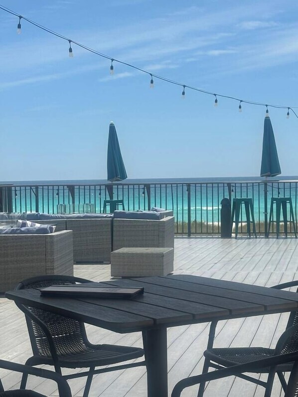 An outdoor seating area with a view of the ocean, featuring wicker furniture and a table. - Arie Escapes in Gulf Breeze | Minutes from the Beach (Gulf Breeze)