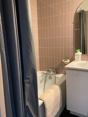 Ein Badezimmer mit einer Badewanne, einem Waschbecken und einem Spiegel.