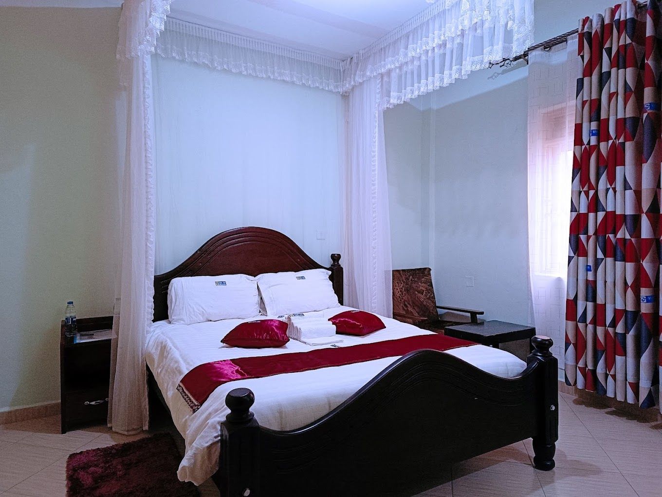 A bed with a headboard, a bedside table, and a chair.