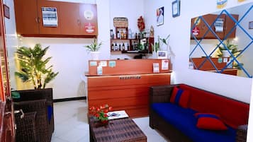 Un espace d’accueil comprenant un comptoir de réception, un canapé, une petite table et une plante.