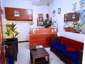 A reception area with a reception desk, a sofa, a small table, and a plant. - Vine Inn Mbarara (Mbarara)