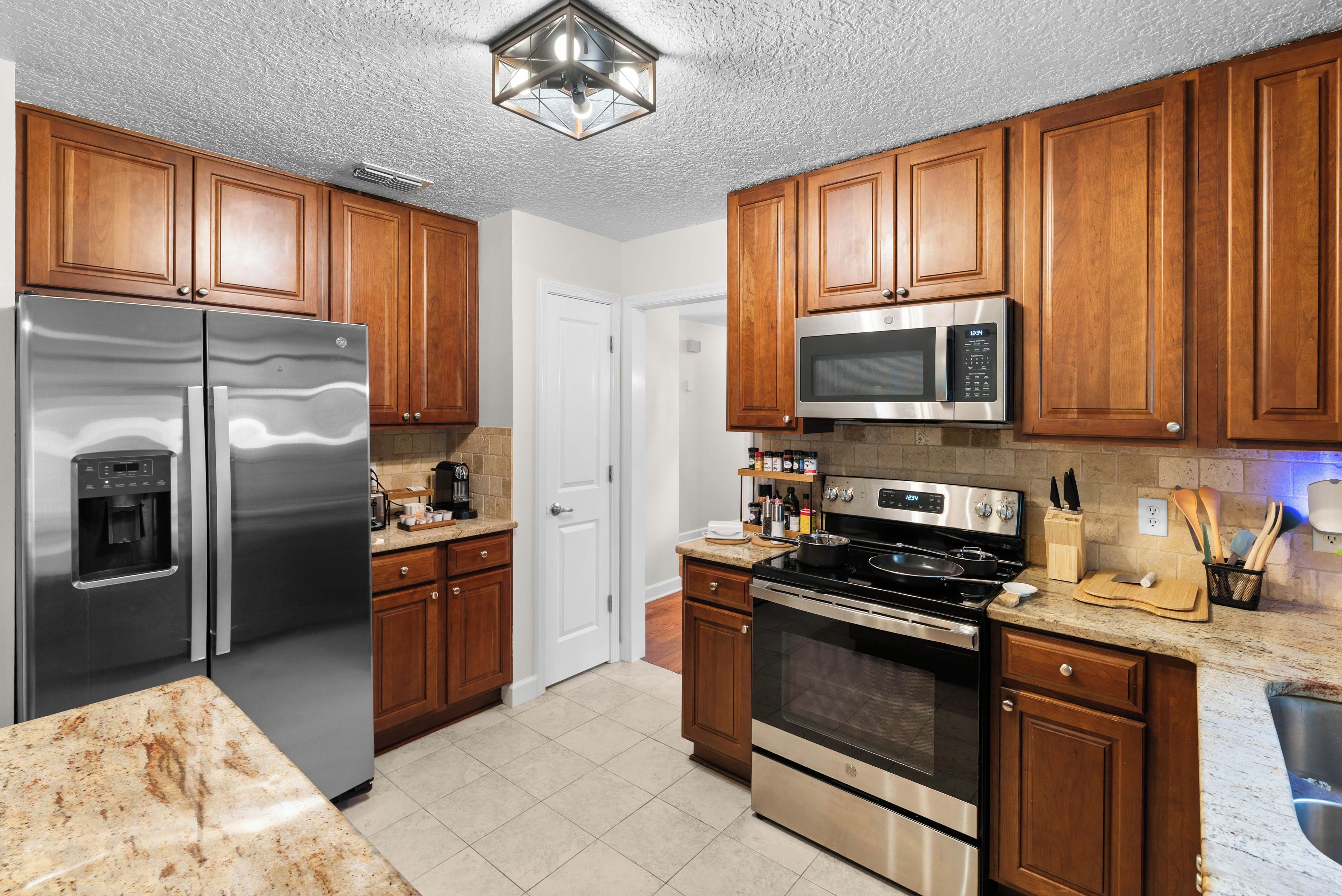A modern kitchen with stainless steel appliances, wooden cabinets, and a granite countertop.