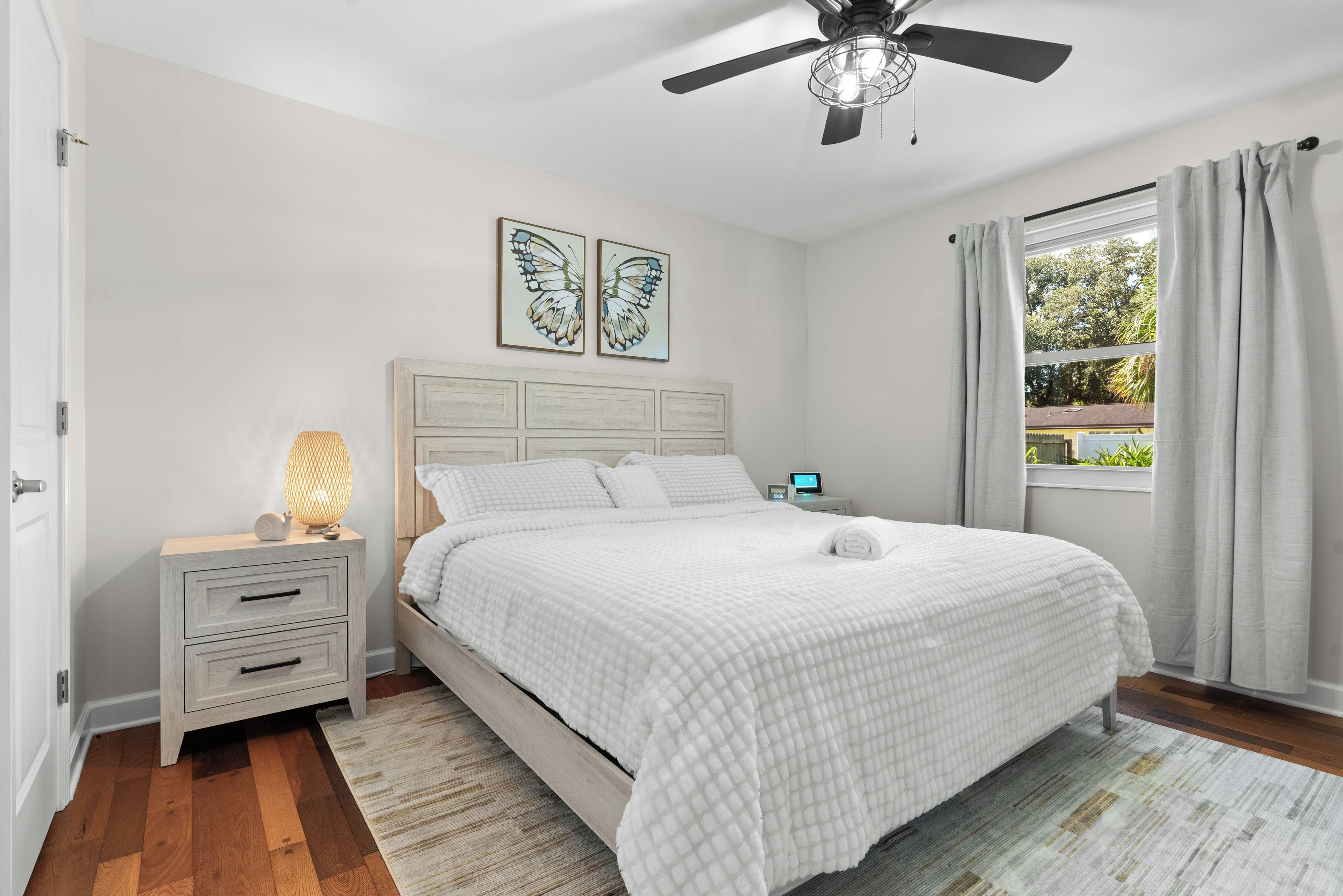 A bedroom with a bed, nightstand, lamp, and a ceiling fan.