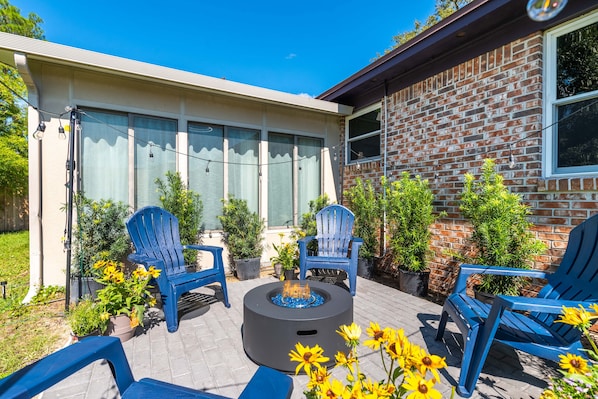 A patio area with outdoor seating, a fire pit, and potted plants.