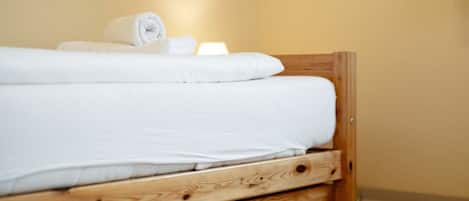 A single bed with a wooden frame and a wooden drawer below it.