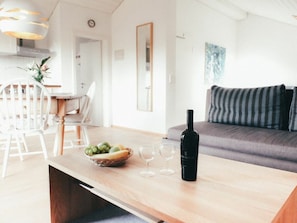 Ein modernes Wohnzimmer mit Holztisch, einer Couch und einem Essbereich mit Stühlen.