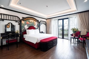 Quarto de hotel com uma cama grande, uma escrivaninha, uma cadeira e vista para o exterior.