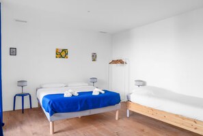 A bedroom with a bed, a bedside table, a lamp, and a small wall art piece. - New Listing (Toulouse)
