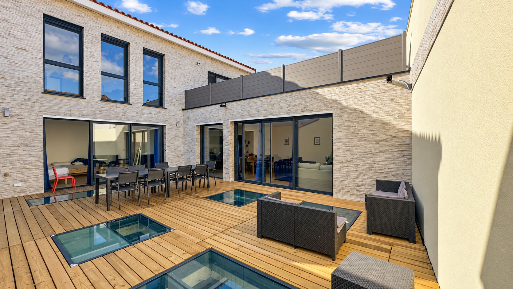 A modern outdoor patio with a pool, seating, and a dining area.