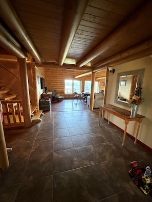 A wooden interior with a tiled floor, a dining area with chairs and a table, and a bench.