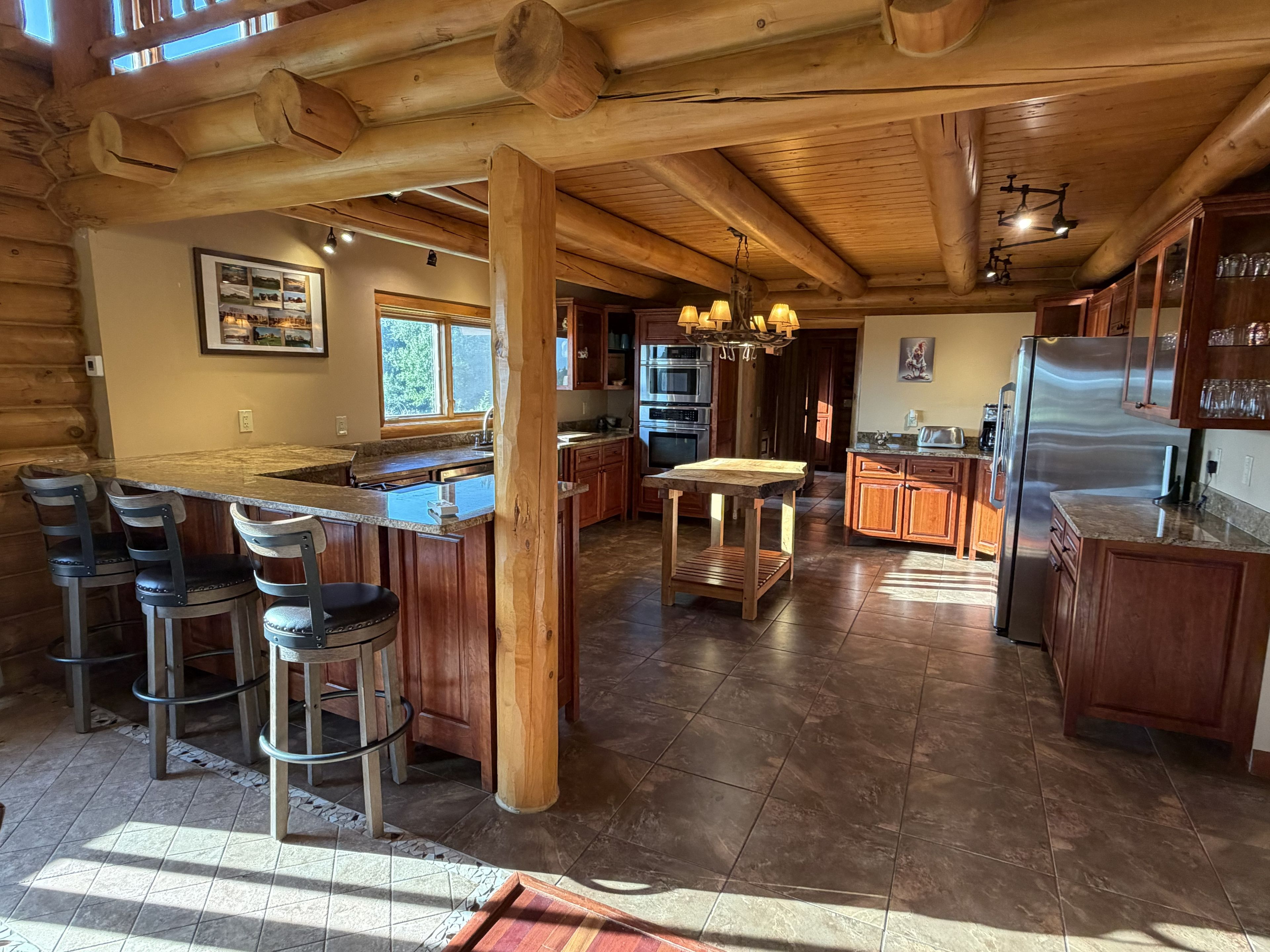 A spacious kitchen with wooden beams, a bar area with stools, and modern appliances.