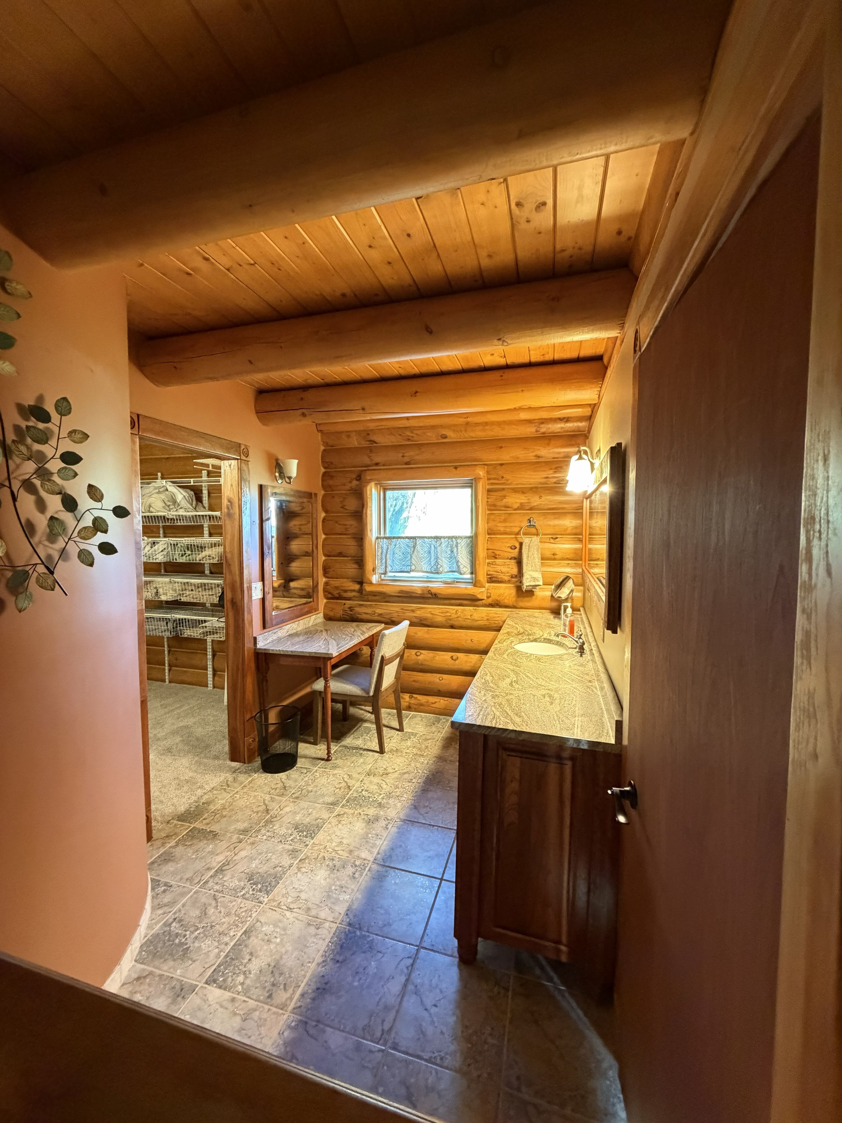 Interior de cabana de madeira com sala de jantar, cozinha com pia e janela que ilumina naturalmente.