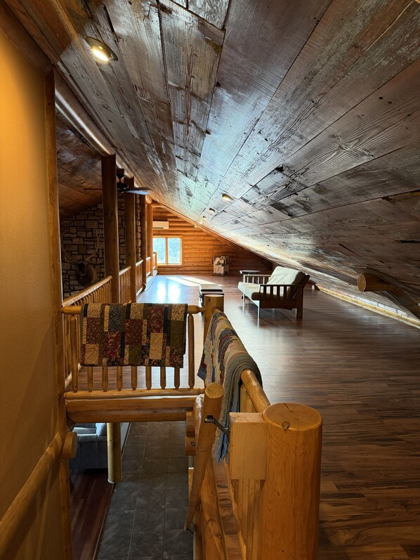 An attic room with wooden beams, a staircase, and a view of the outside. - High Country Ranch 4300 sf Log Home, 4 bedrooms (La Crescent)