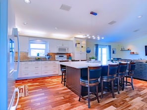 A modern kitchen with a central island, white cabinetry, and a wooden floor. - Ultimate Waterfront Escape: Pool, Kayaks & Fun! (Cape Coral)