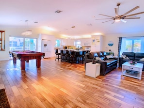 A spacious living area with a pool table, a sofa, and a dining area with chairs. - Ultimate Waterfront Escape: Pool, Kayaks & Fun! (Cape Coral)