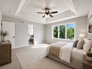 A bedroom with a bed, a ceiling fan, a window with a view of trees, and a door leading to a bathroom. - Luxury Furnished Home - 90 Day Minimum Stay (Lincoln)