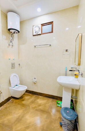 Un baño con inodoro, lavamanos, espejo y zona de ducha.