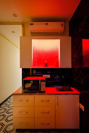 Una cocina con microondas, un armario con luz roja y un aire acondicionado instalado en el techo.
