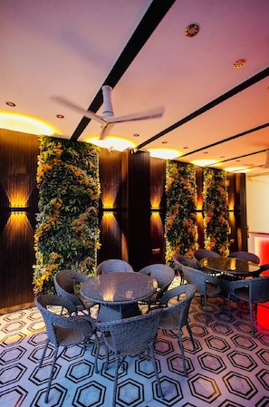 Una habitación con ventilador de techo, pared con jardines verticales y suelo con estampado hexagonal.