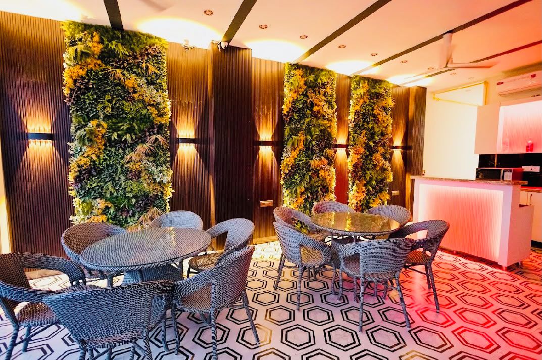 A room with a round table and wicker chairs, a vertical garden wall, and a patterned floor.