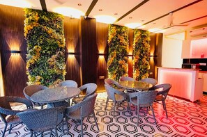 A room with a round table and wicker chairs, a vertical garden wall, and a patterned floor.