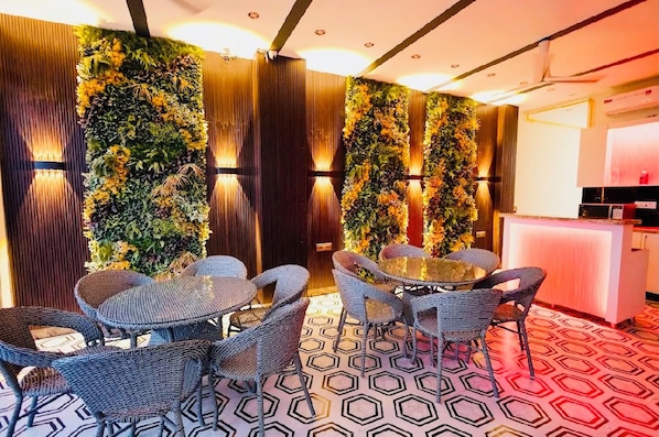 A room with a round table and wicker chairs, a vertical garden wall, and a patterned floor. - Pauls Guest Inn (New Delhi)