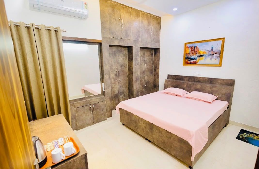 A bedroom with a bed, a wardrobe, a desk with a tray of items, and a painting on the wall.