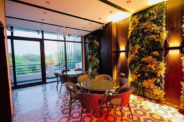 A modern interior with a dining area featuring wicker furniture and a large window.