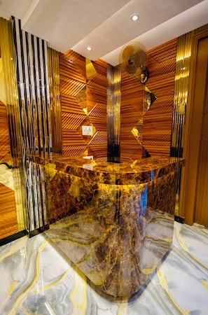 A reception area with a marble counter, wooden paneling, and a ceiling fan.