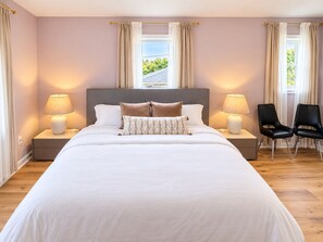 Een slaapkamer met een groot bed, twee bedlampen, een nachtkastje en een stoel.