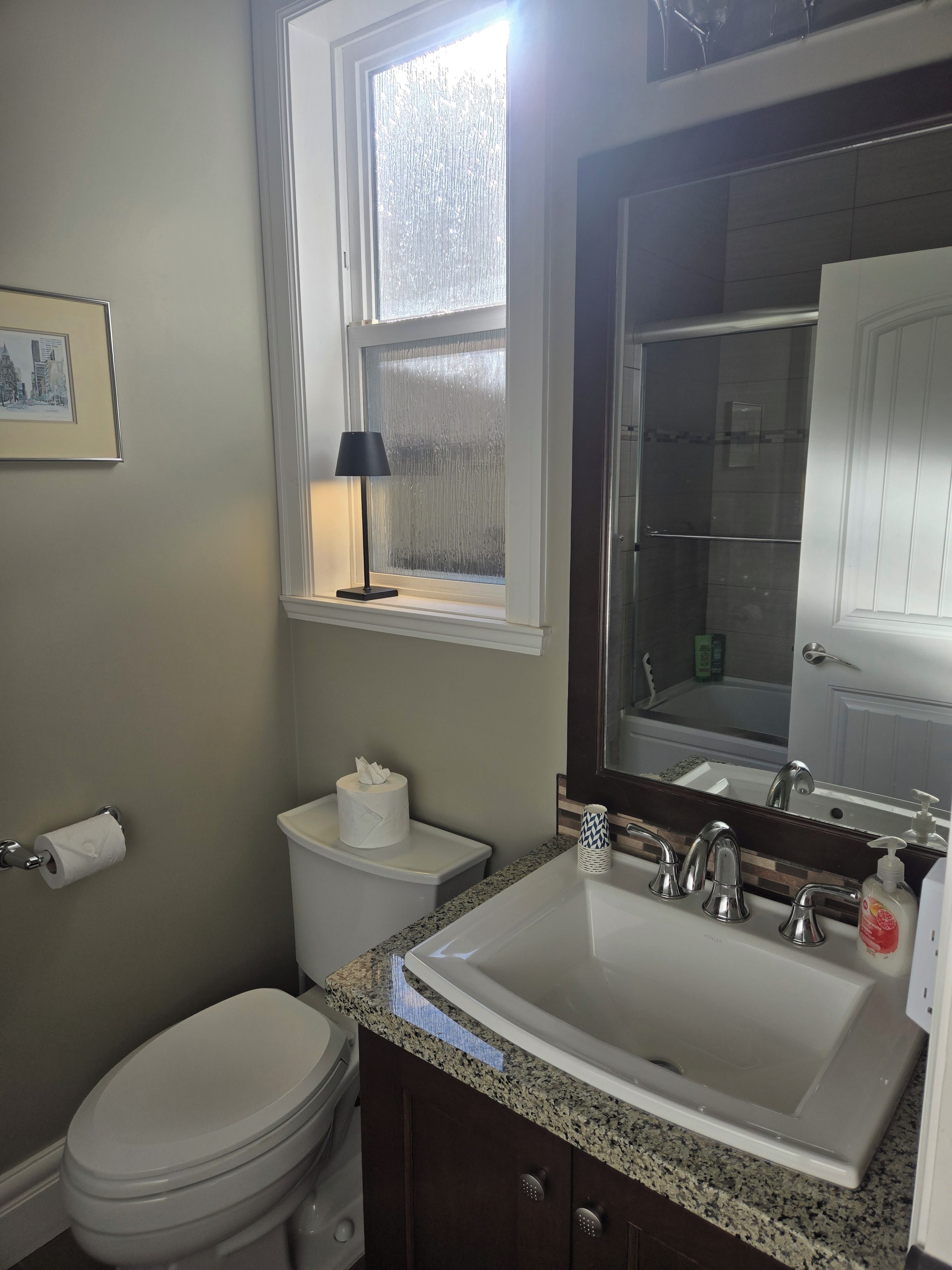 A bathroom with a toilet, sink, and window.