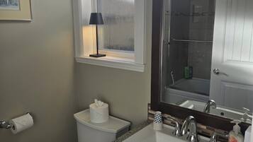 A bathroom with a toilet, sink, and window.