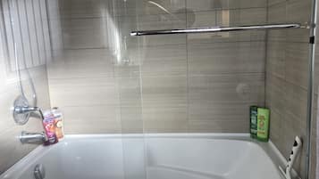 A bathroom with a bathtub, a shower, and a window.
