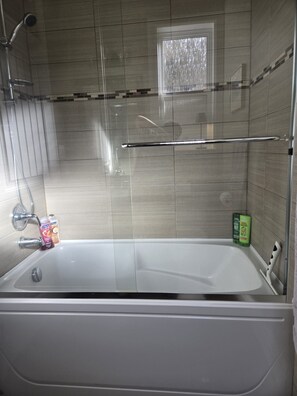 A bathroom with a bathtub, a shower, and a window. - Near YVR Airport, 5 min to City Centre, Public transit. Bedroom w/ 2 twin beds! (Richmond)