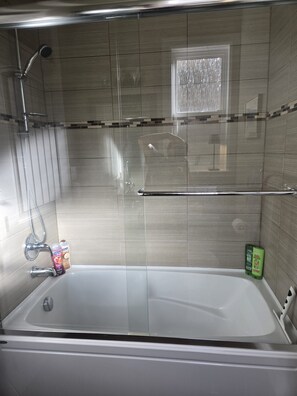 A modern bathroom with a bathtub, shower, and glass-enclosed shower area. - Near YVR Airport, 5 min to City Centre, Public transit. Bedroom w/ 2 twin beds! (Richmond)