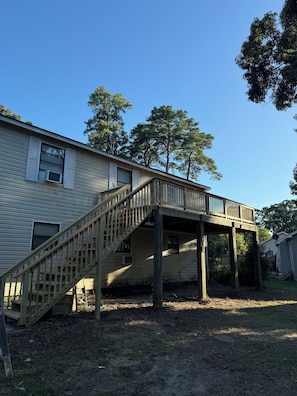 A two-story house with a wooden deck and a staircase leading to an upper level.