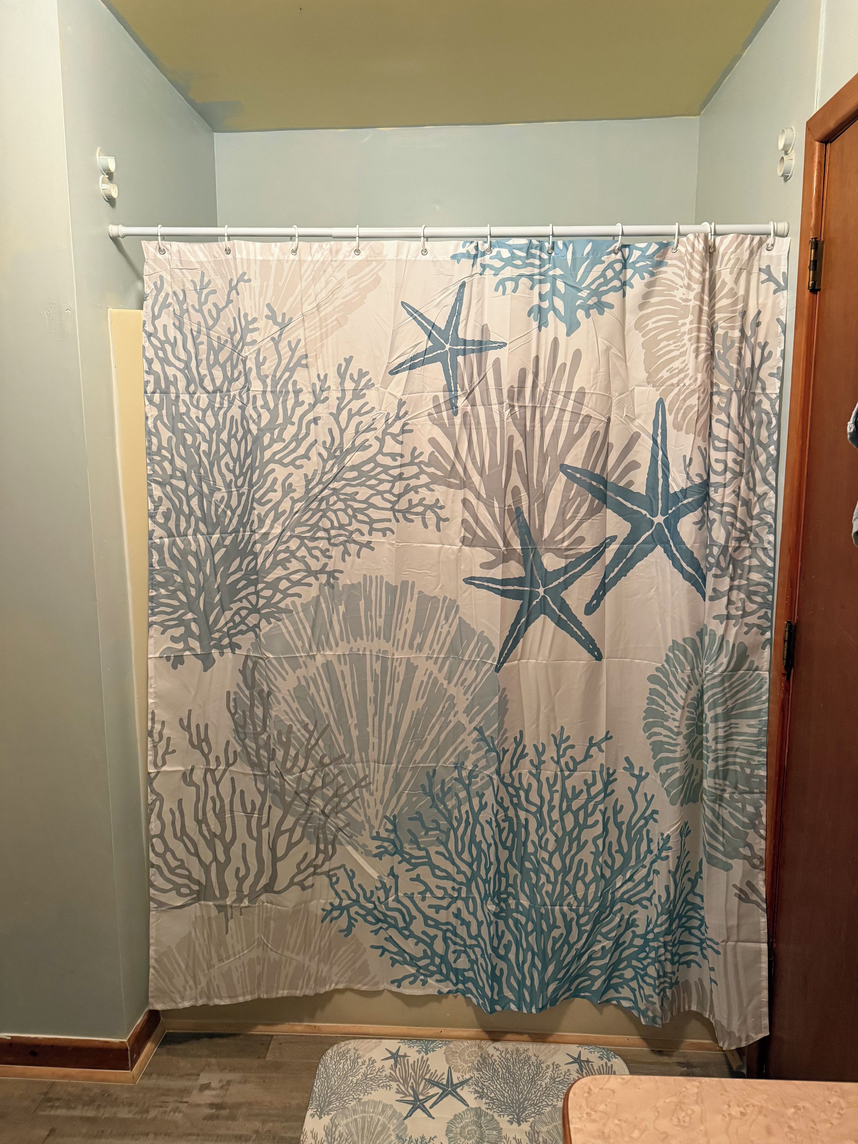 Un baño con cortina de ducha con diseño de arrecife de coral.
