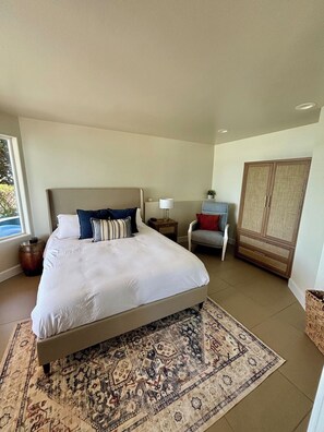 A modern bedroom with a large bed, a bedside table, a chair, a wardrobe, and a patterned rug. - Lakefront, Private Dock & Hot Tub - Sleeps 14 (Moses Lake)