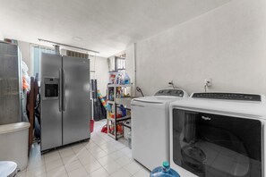 Lavanderia con lavatrice, asciugatrice e cesti per bucato impilati.
