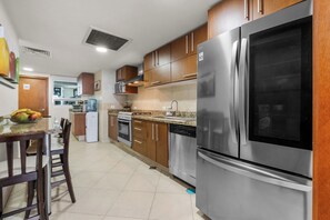 Una cucina moderna con elettrodomestici in acciaio inossidabile, pensili in legno e un'area pranzo con sedie.