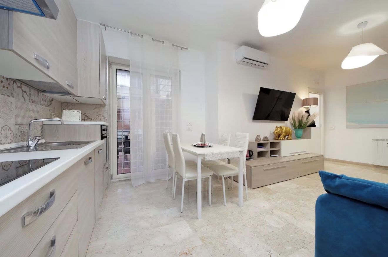 Una cucina moderna con zona pranzo, TV a parete e un divano blu.