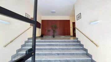 Una scala in marmo con ringhiere nere che conduce a una stanza con una porta in legno e una pianta in vaso.