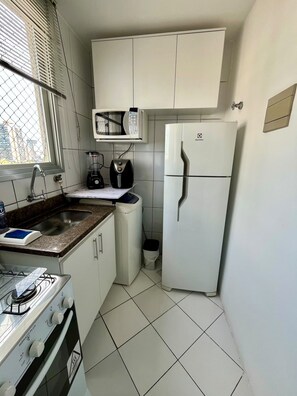 A compact kitchen with a gas stove, a microwave, a refrigerator, and a sink. - New Listing (Vila Velha)