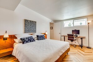 A bedroom with a bed, bedside lamps, a desk with a computer, and a window. - Thoughtfully Refreshed MCM.  3 Beds with Pool.  28+ day Rentals (Palm Desert)